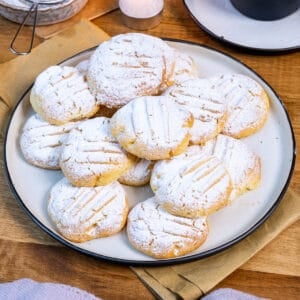 Melting moments cookies topped with powdered sugar served on a plate.