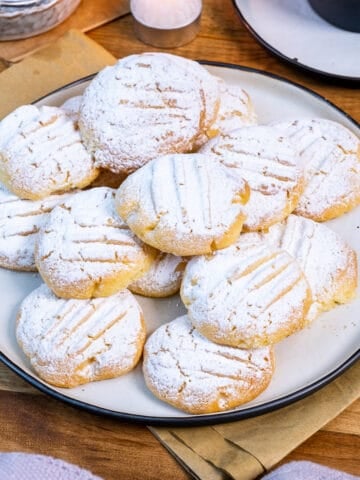 Melting moments cookies topped with powdered sugar served on a plate.