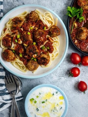 Tomato Chili Sauce Meatballs served on pasta in a white bowl.