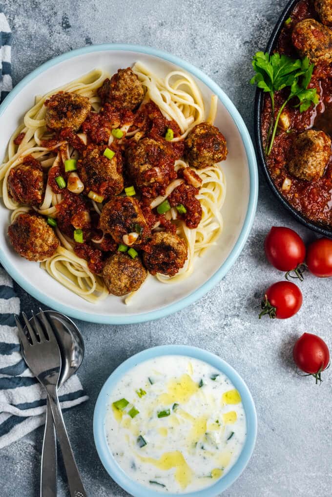Tomato Chili Sauce Meatballs served on pasta in a white bowl.