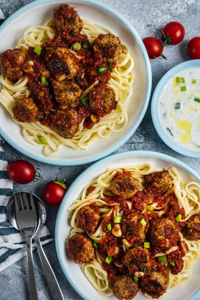 Tomato Chili Sauce Meatballs served on pasta in two white bowls.