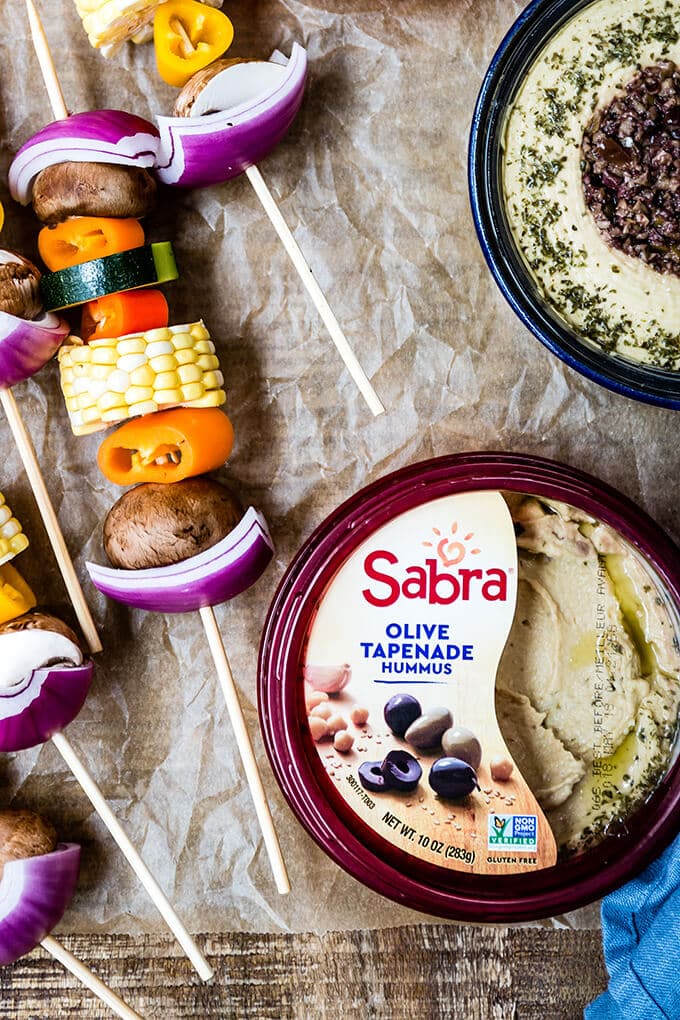 Veggie Kabobs with a simple tangy marinade are so tasty and healthy. So vibrant and packed with flavors, these kabobs make a a great side dish to any meal or a perfect summer appetizer. #vegetarian #kabobs #summerparty #partyfood #meatless #appetizer #ad @sabradips Vegetarian kabobs and hummus bowls on baking paper