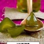 Unripe fig jam pieces on a wooden spoon with a jar in the background.