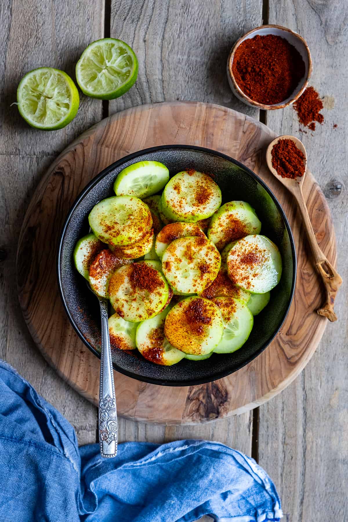 Cucumber slices with chili powder in a black bowl.