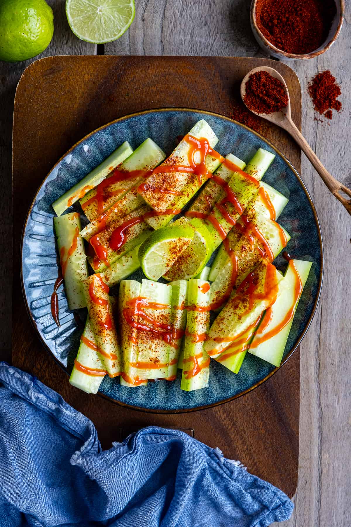 Sliced cucumber flavored with chili powder and hot salsa drizzled on them.