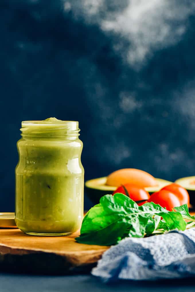 Avocado dressing in a glass jar on a wooden board