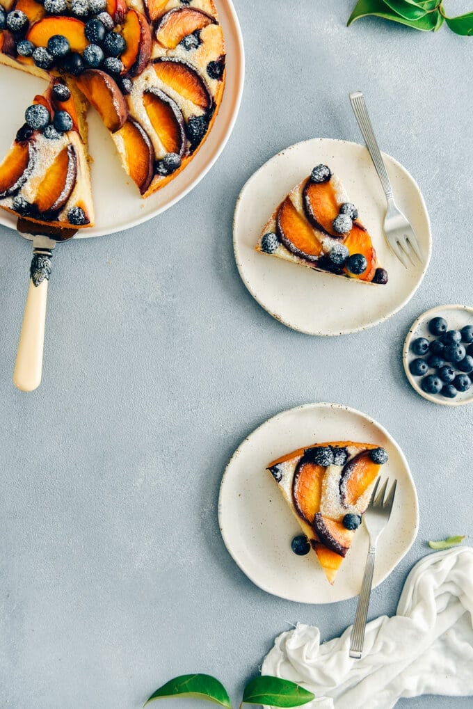This Blueberry Peach Coffee Cake is a luscious cake that is sure to be a crowd pleaser. Made with olive oil and kefir, this simple cake is moist, tender and so light. #peachcake #peachcoffeecake #peachrecipe #coffeecake #kefircake #kefirrecipes Peach coffee cake recipe with kefir photographed on white plates