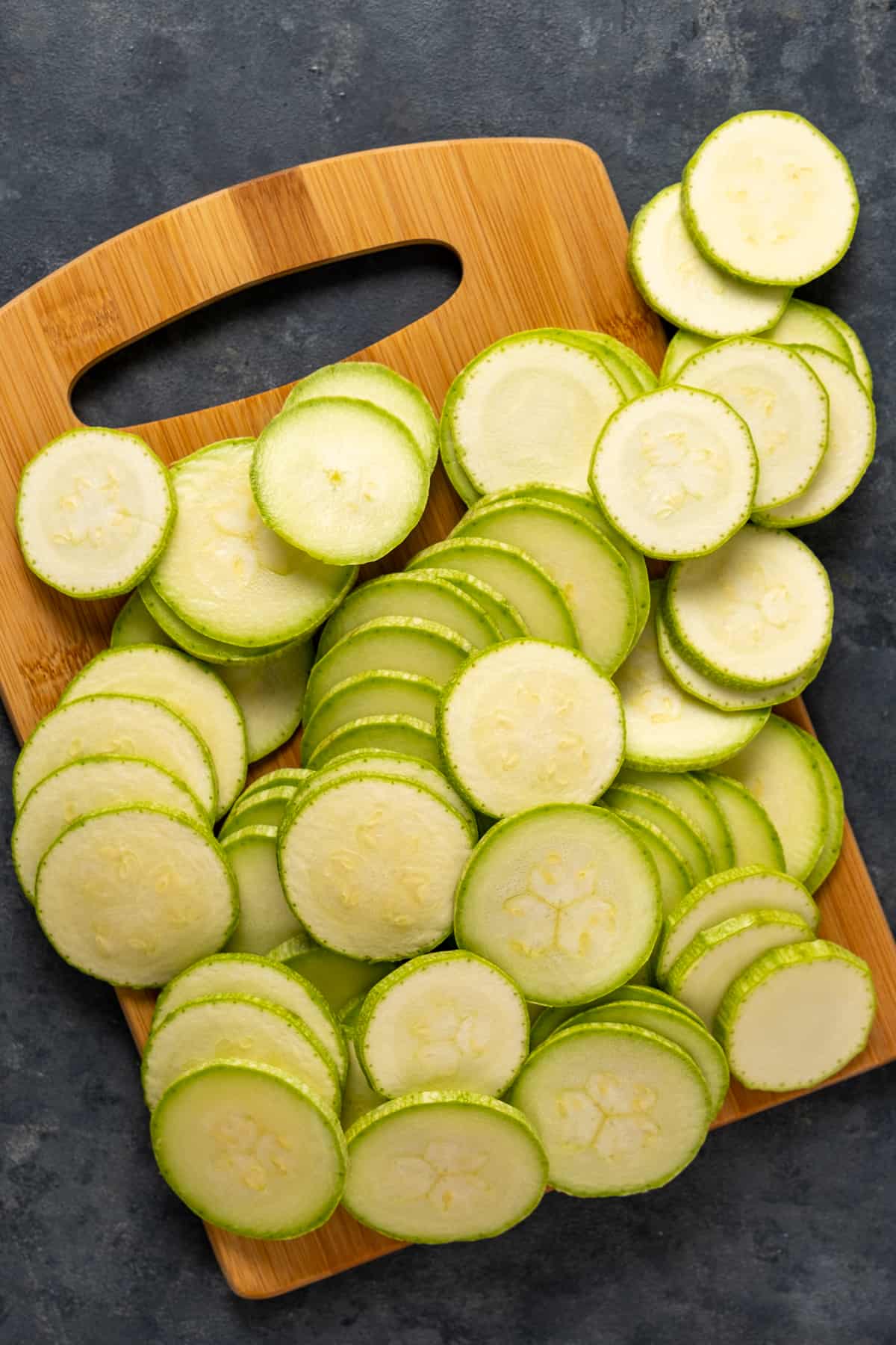 Super thin zucchini slices on a wooden board.