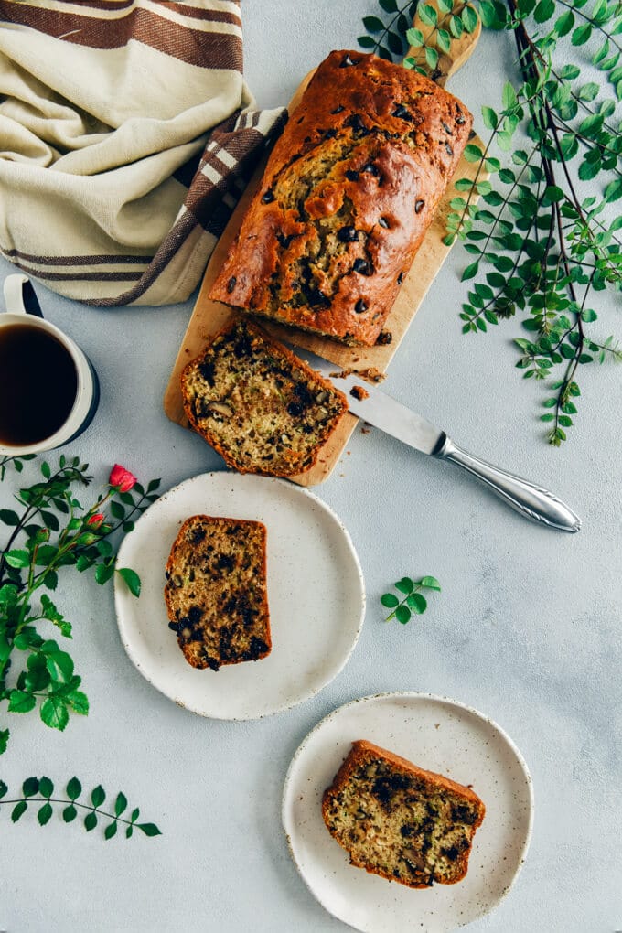 Chocolate chip zucchini bread sliced on a wooden board and served on two white plates