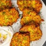 Mucver patties served with yogurt on a white plate.