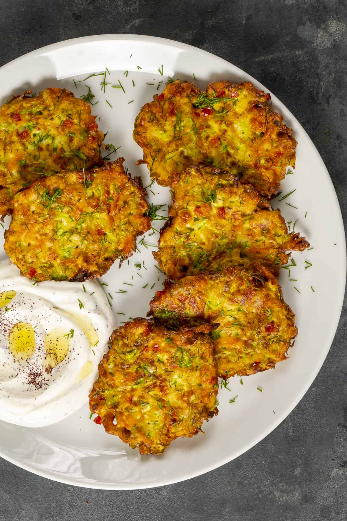 Mucver patties served with yogurt on a white plate.