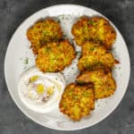 Mucver patties served with yogurt on a white plate.