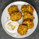 Mucver patties served with yogurt on a white plate.