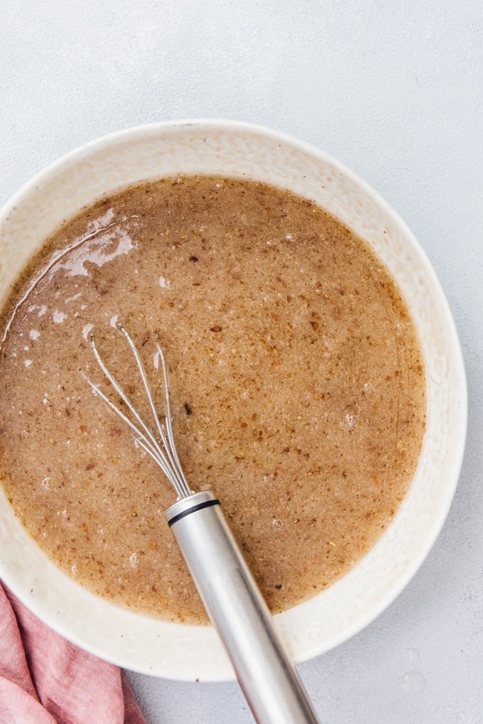 Make your flax egg with two ingredients and use it in your vegan recipes. #veganbaking #veganegg #flaxegg Flax egg in a bowl with a hand whisk