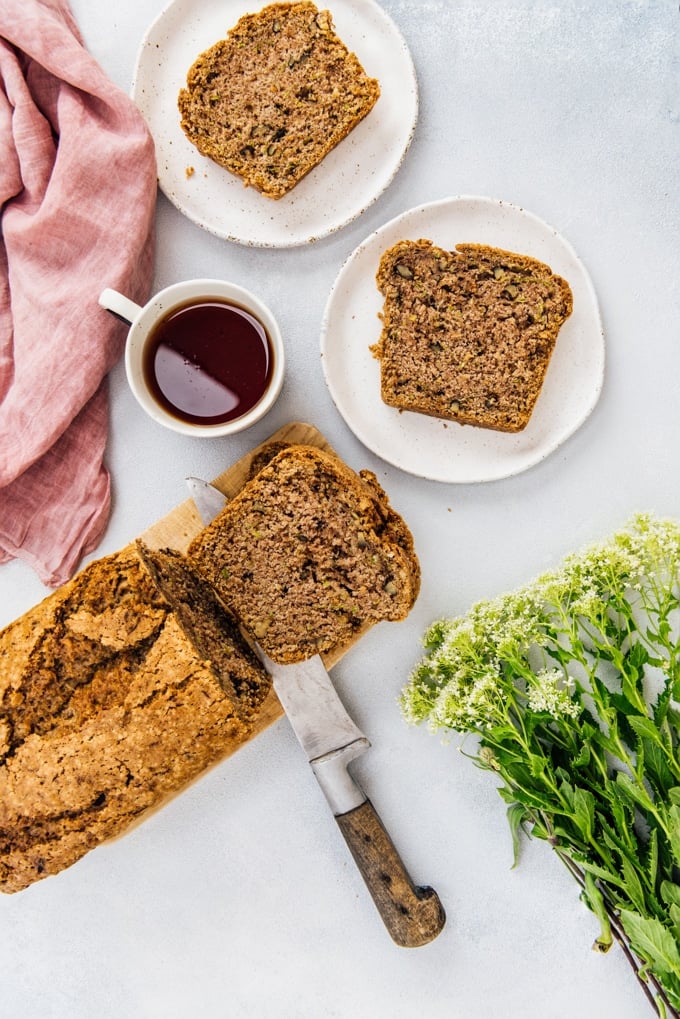BEST vegan zucchini bread. Super fluffy and wonderfully moist. Feel the crunch of walnuts in every bite. #veganbaking #veganbread #zucchinibread #veganzucchinibread Best vegan zucchini nut bread sliced and served with tea and flowers