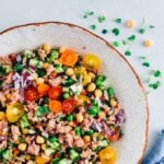 Chickpea tuna salad with tomatoes and cucumbers in a white bowl.