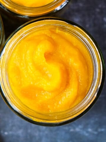 Boiled pumpkin puree in jars on a dark background.