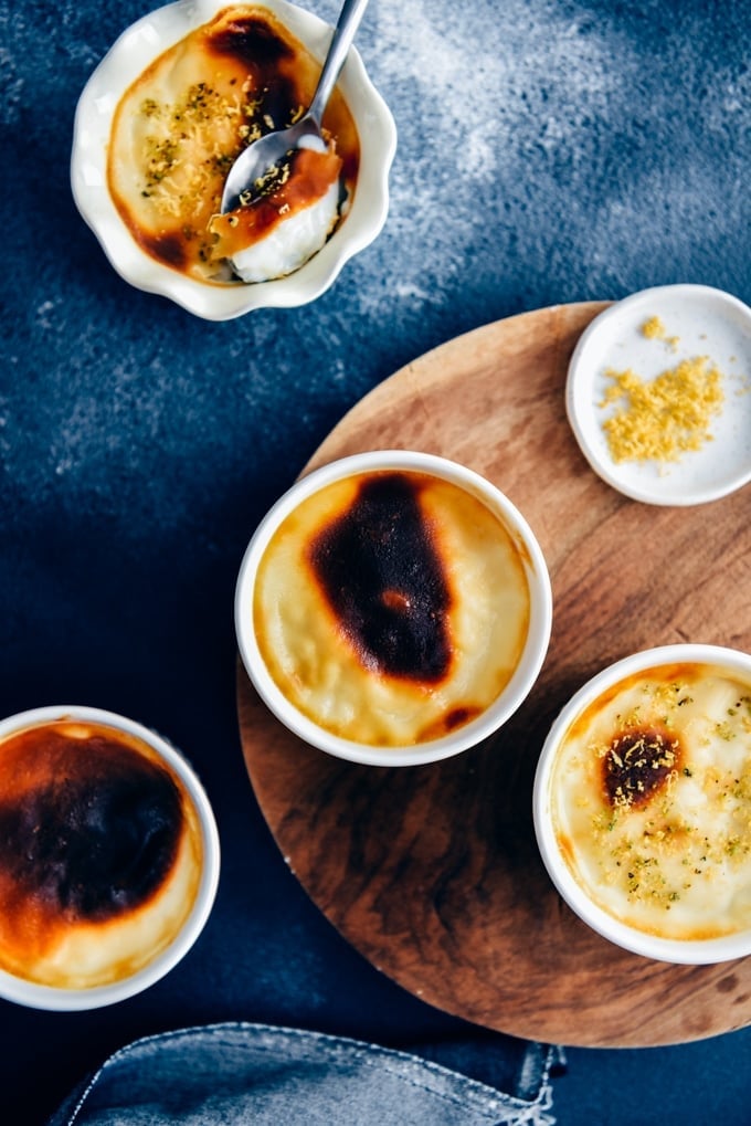 Baked rice pudding in white ramekins served on a wooden board.