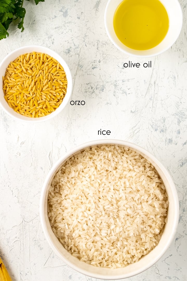 Orzo, rice and olive oil are in separate bowls on a white background.