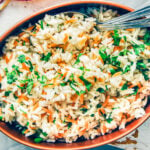 Homemade rice pilaf with orzo and a little parsley in an oval copper pan.