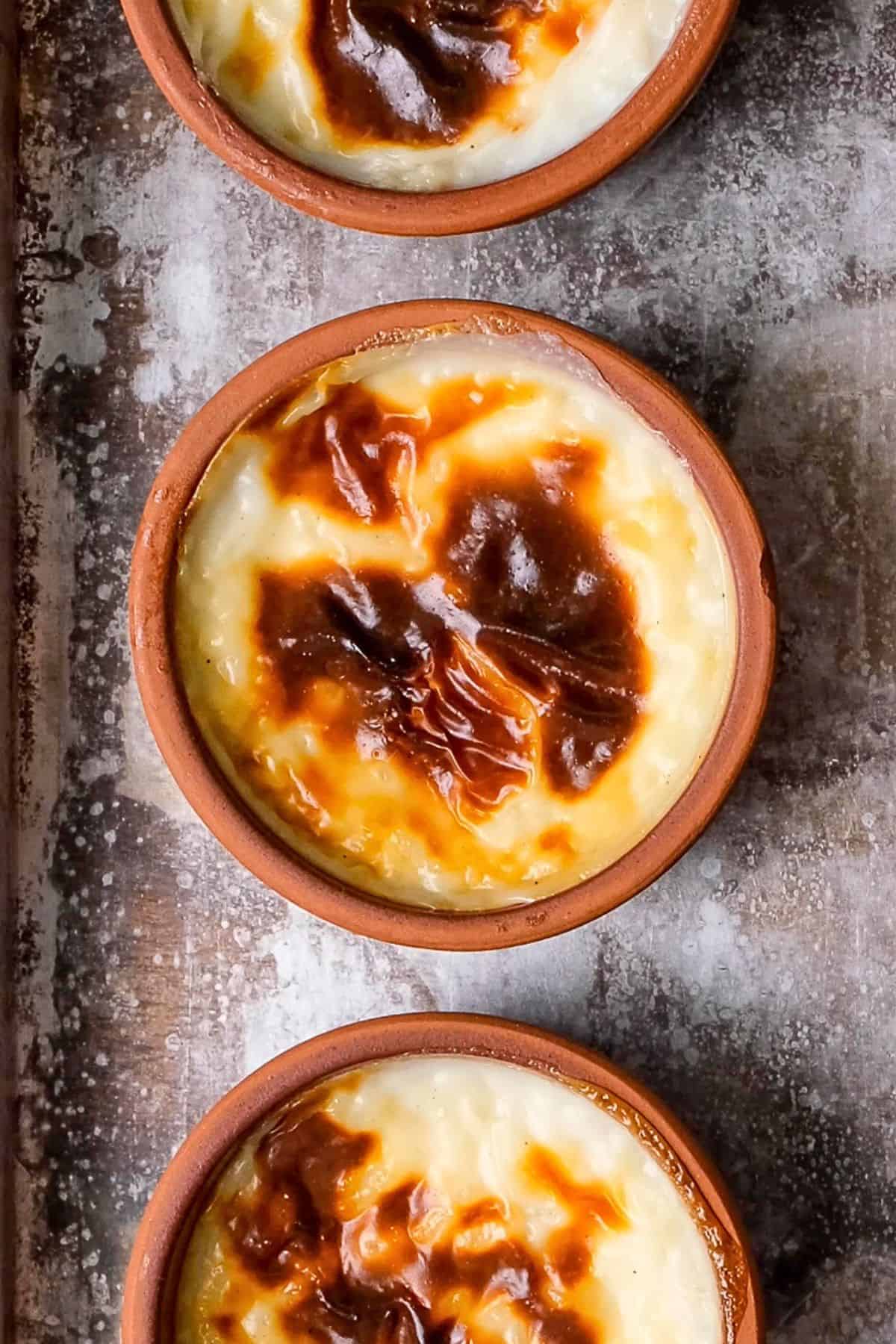 Close-up of Turkish baked rice pudding (fırın sütlaç) in clay bowls with beautifully caramelized tops.