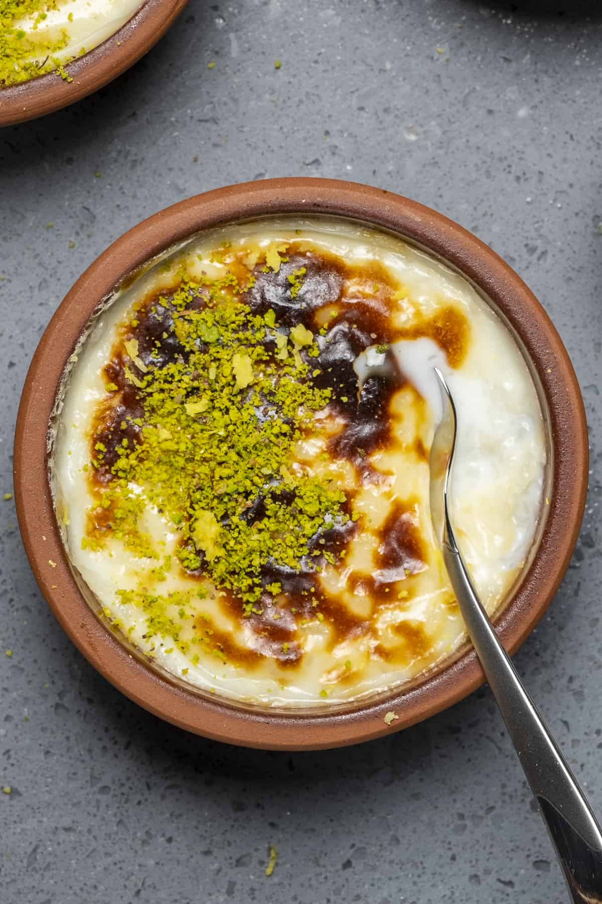 Rice pudding with a golden top in a small bowl and a spoon in it.