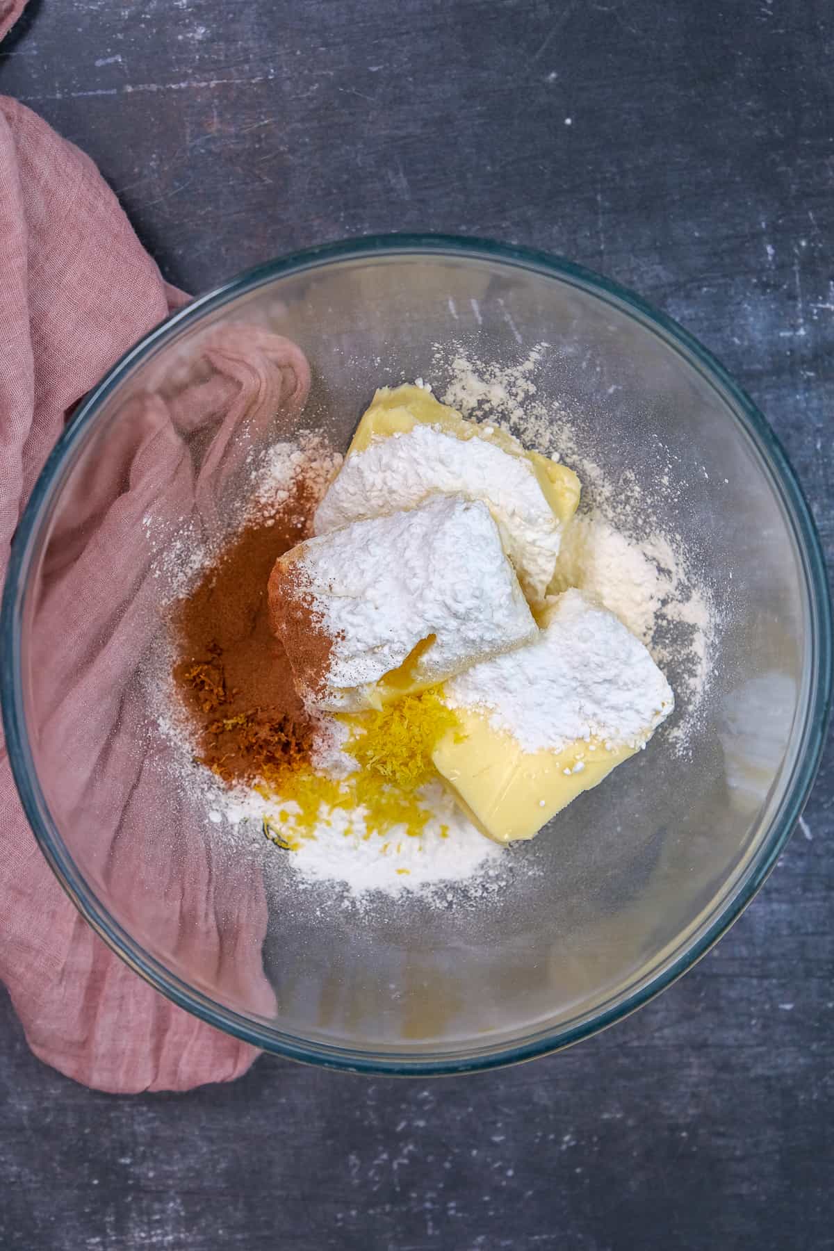 Butter, powdered sugar, cinnamon and lemon zest in a glass mixing bowl.