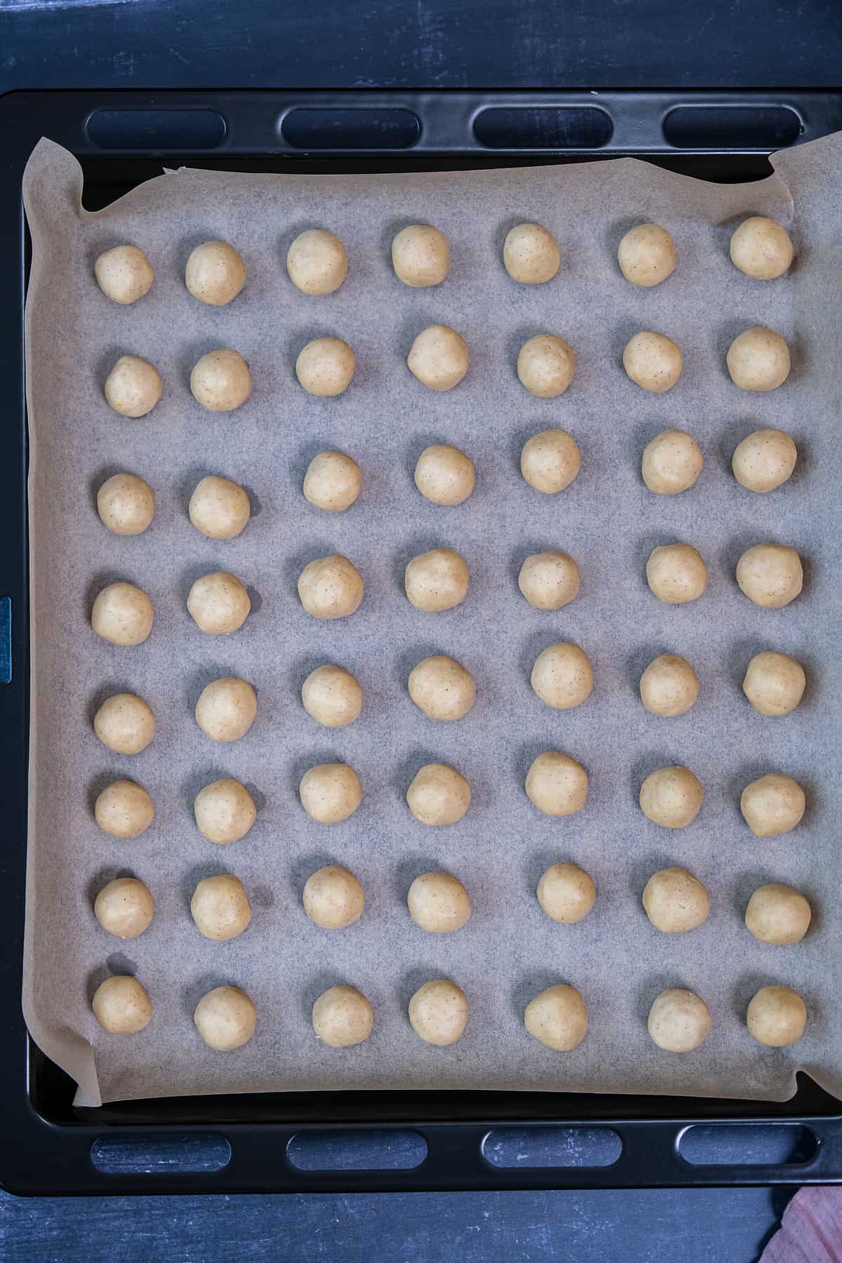 Mini melt away cookies on a parchment paper lined baking sheet.