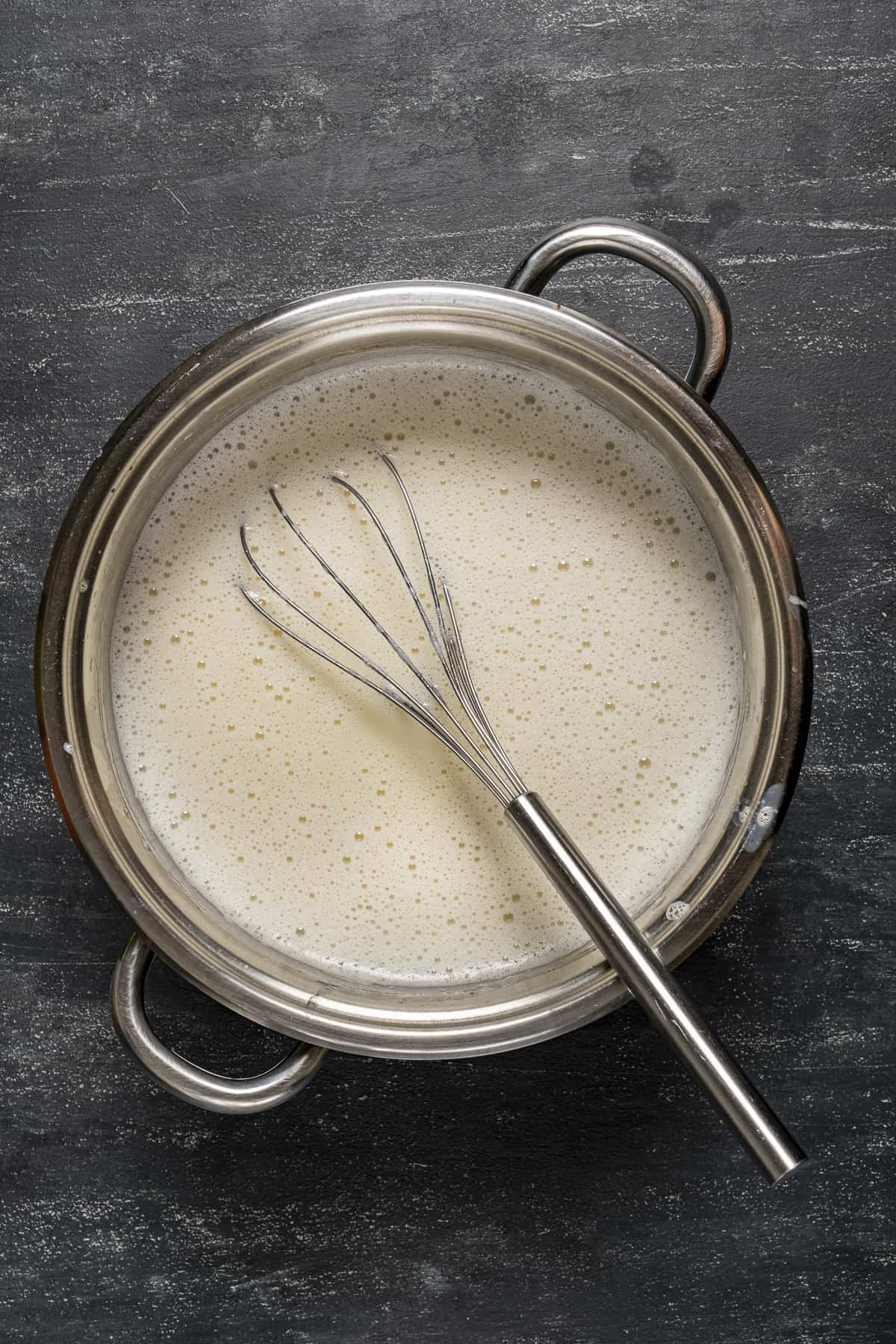 Salep in a saucepan and a hand whisk inside it.