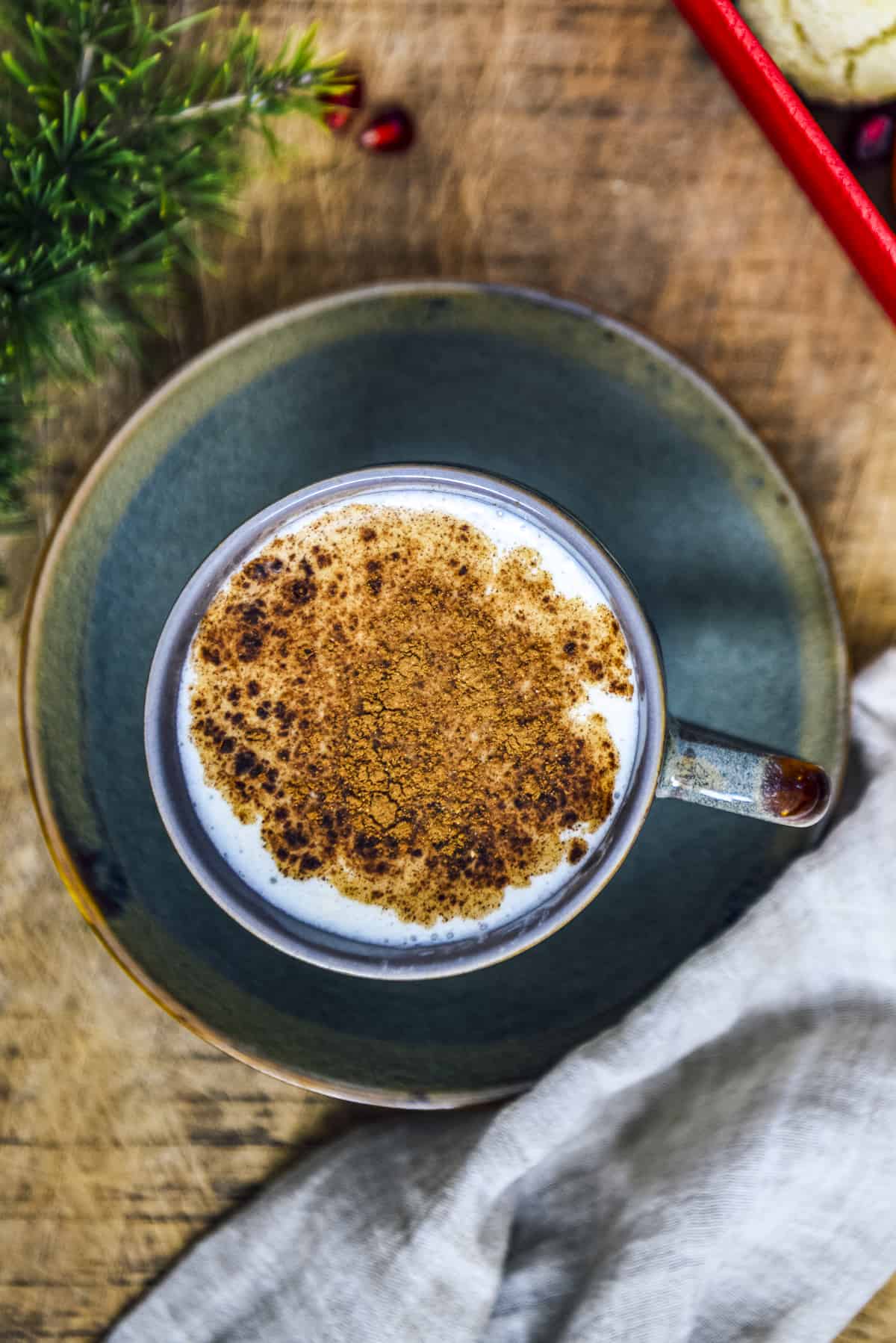 Salep topped with cinnamon in a cup photographed on a wooden board.