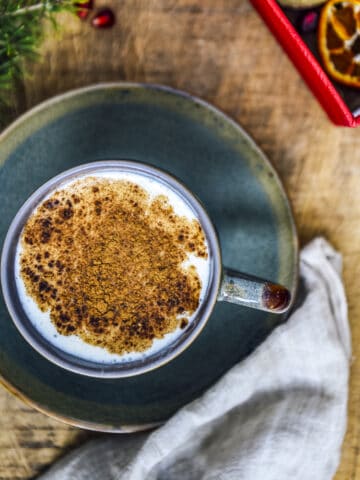 Salep drink topped with cinnamon in a cup on a wooden background.