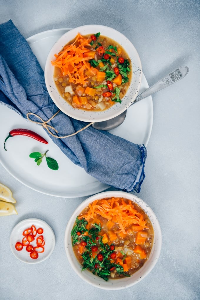 Two bowls of vegan carrot soup with rice and lentils.