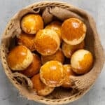 Homemade rolls with golden top in a basket shot from top view.