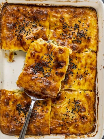 Cheese borek sliced in square in a baking pan.