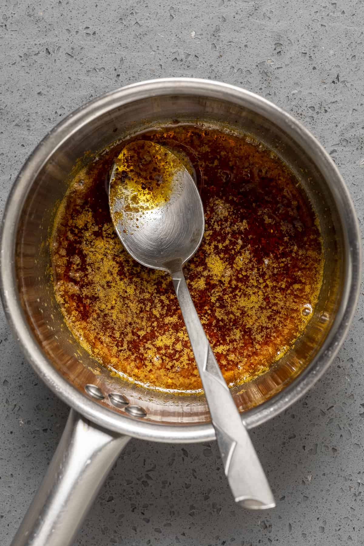 Spiced butter sauce in a small saucepan and a spoon inside it.