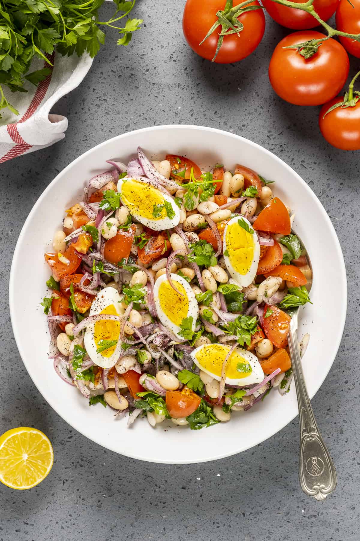 Bean salad topped with hard boiled eggs in a white bowl.