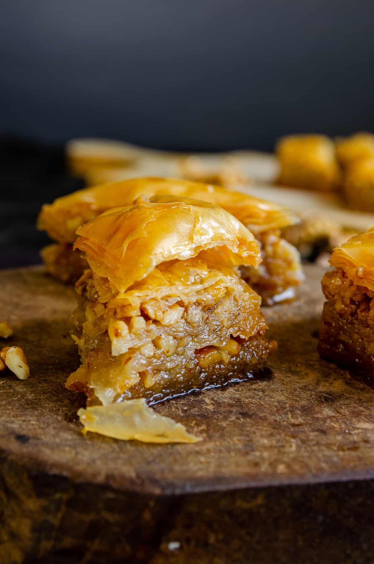 A close shot of a baklava slice filled with walnuts on a wooden serving board.
