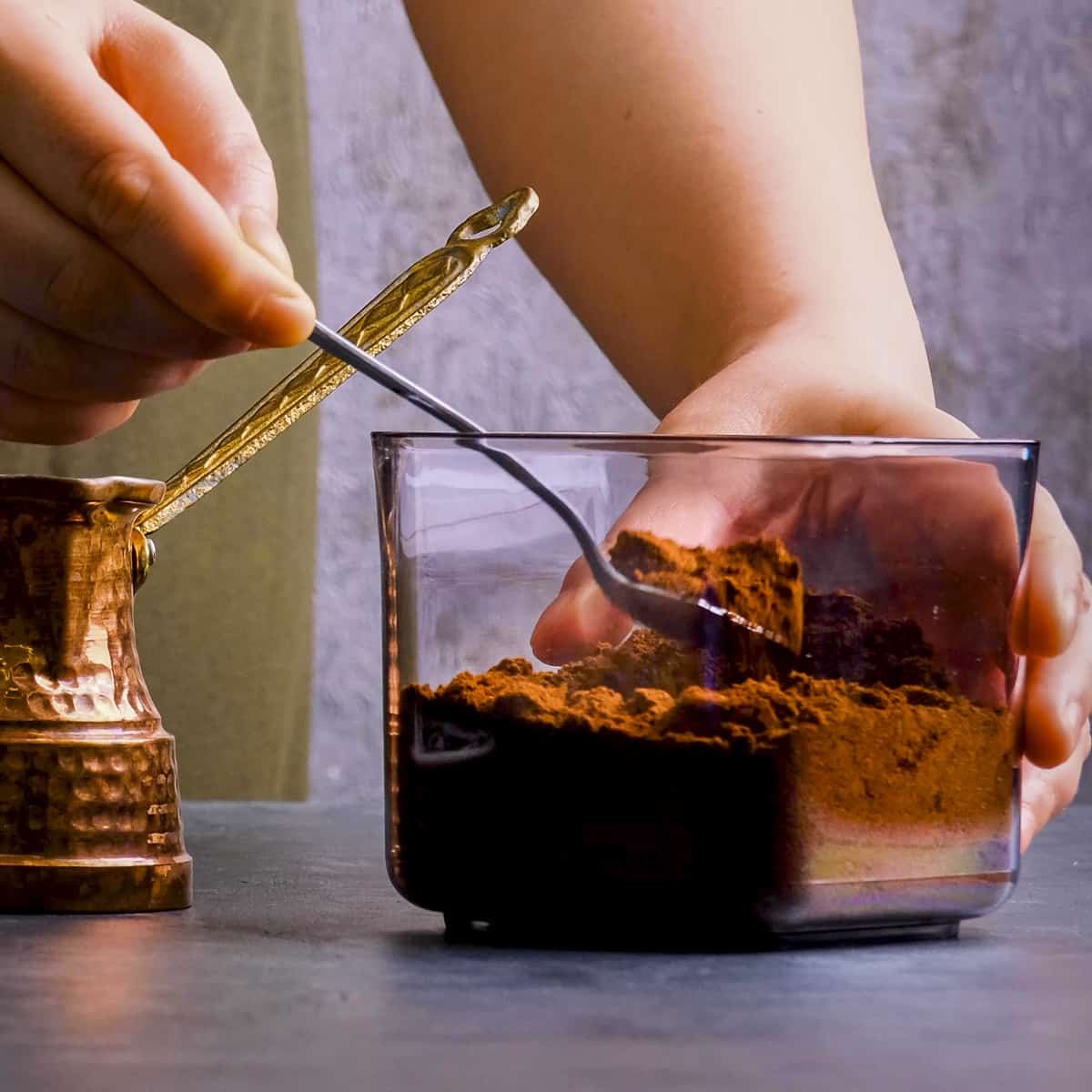 Woman getting a spoonful of ground Turkish coffee from a jar.