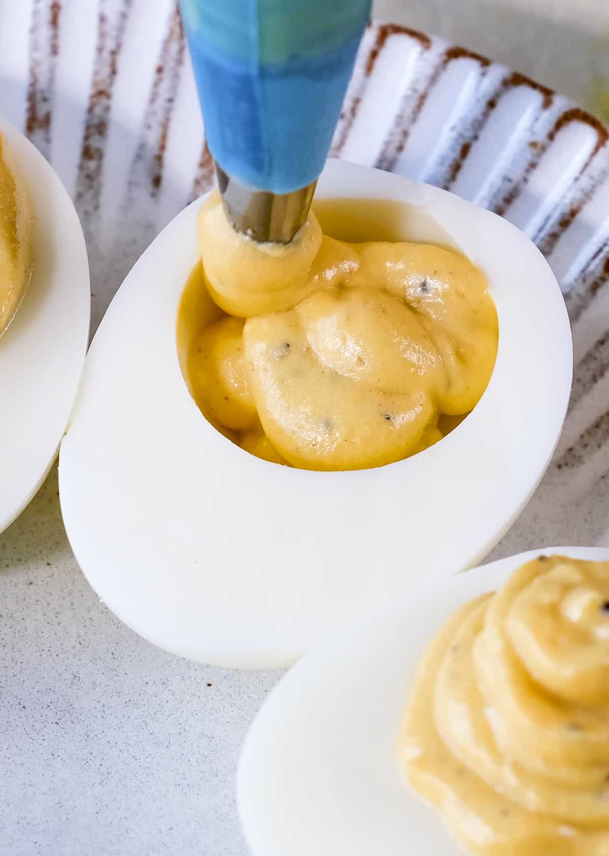 A piping bag filling the egg white halves with the egg yolk mixture.