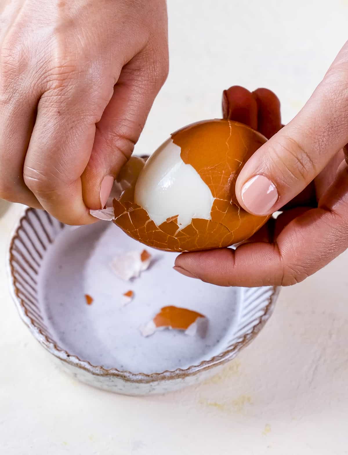 Hands peeling a hard boil egg.