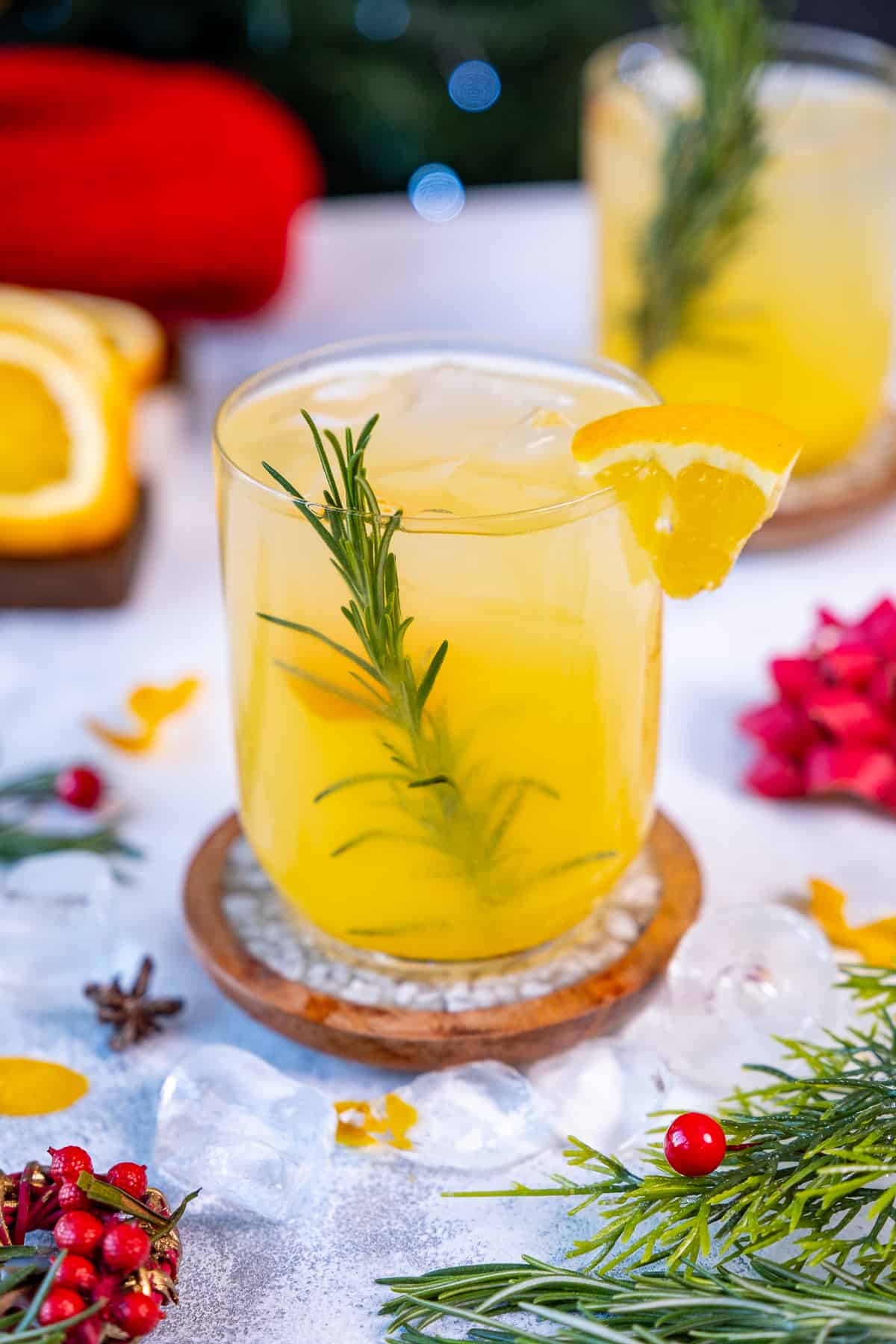 Orange vodka cocktail in a glass garnished with an orange slice and rosemary.