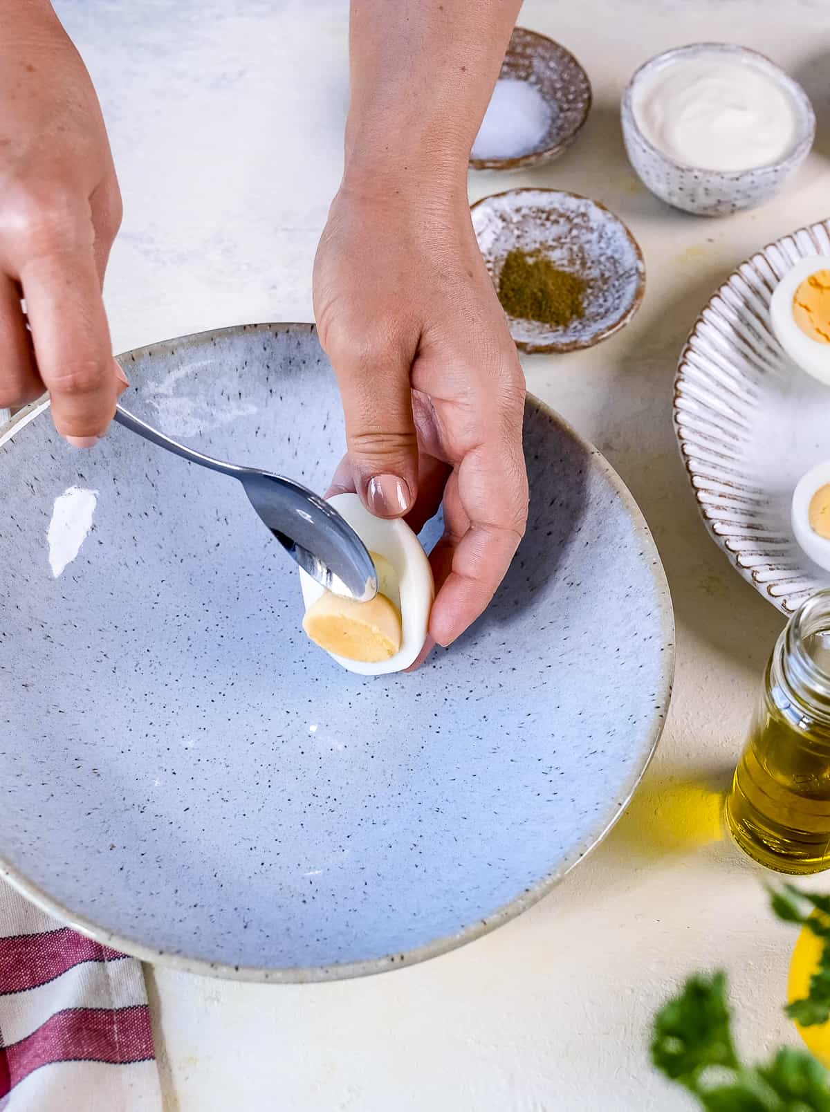Hands removing a cooked yolk from egg white with a spoon.