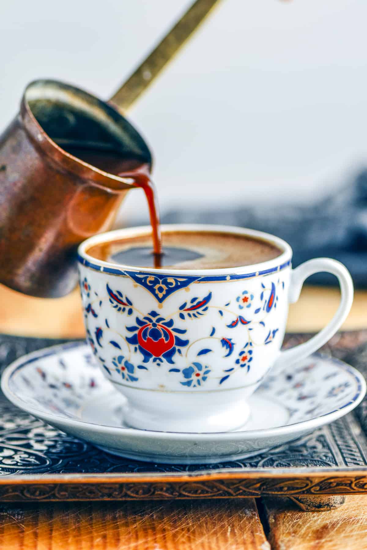 Pouring authentic Turkish coffee from a copper coffee pot into a Turkish style cup.