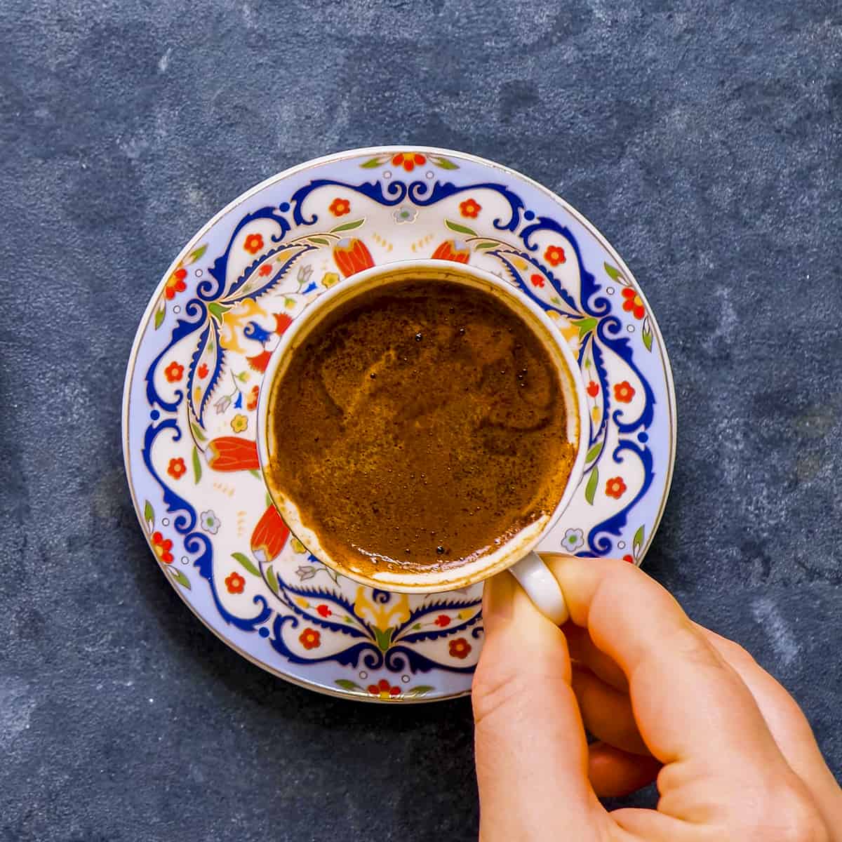 A hand holding a Turkish coffee cup.