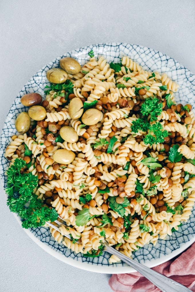 Pasta with vegan bolognese sauce, parsley and green olives served a salad.