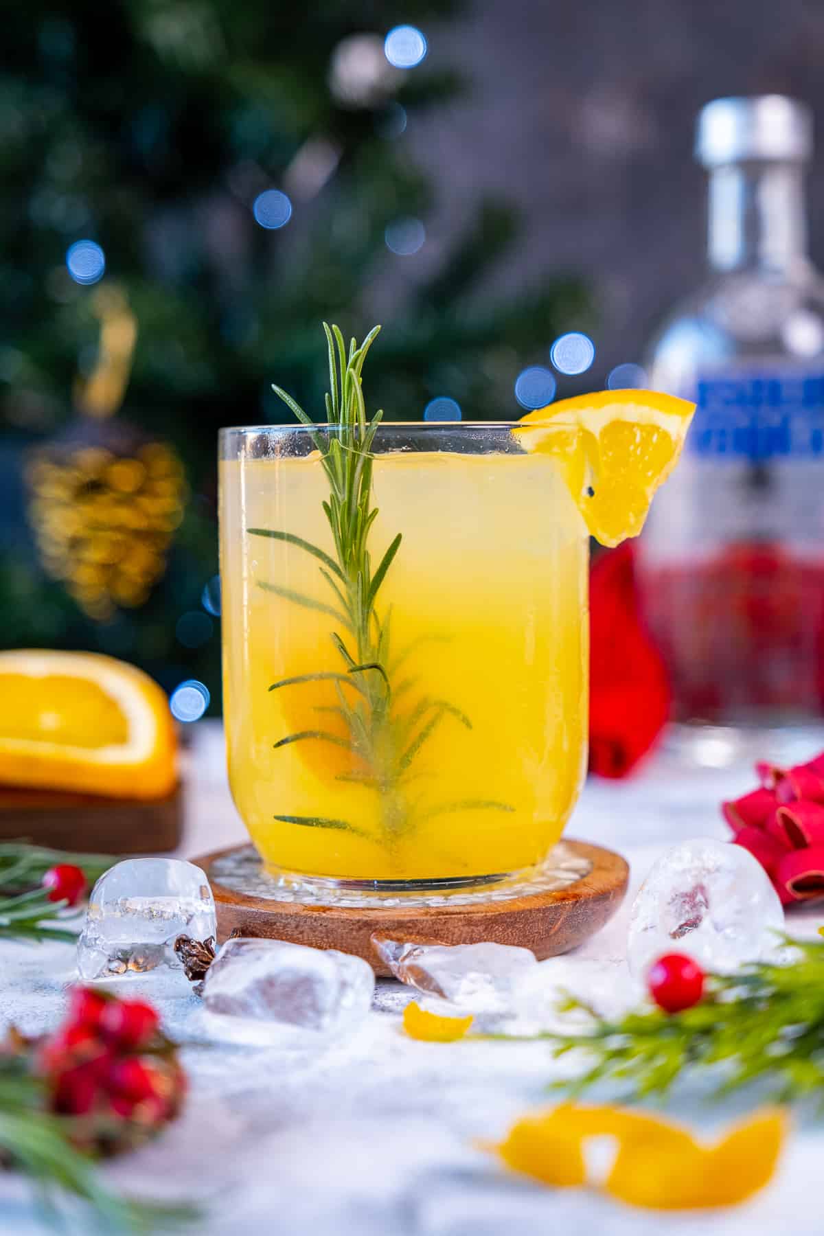 Orange vodka cocktail in a glass garnished with an orange slice and rosemary.
