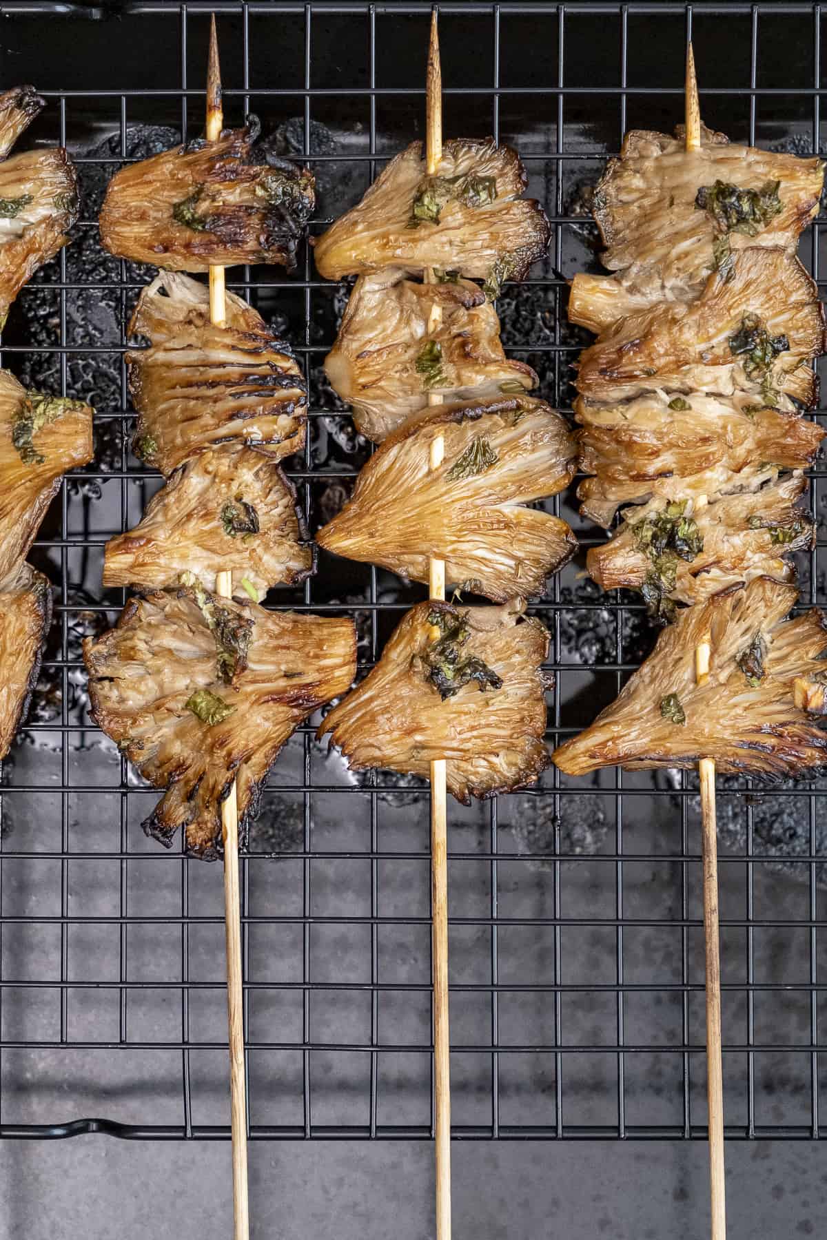 Cooked oyster mushroom skewers on a grill.