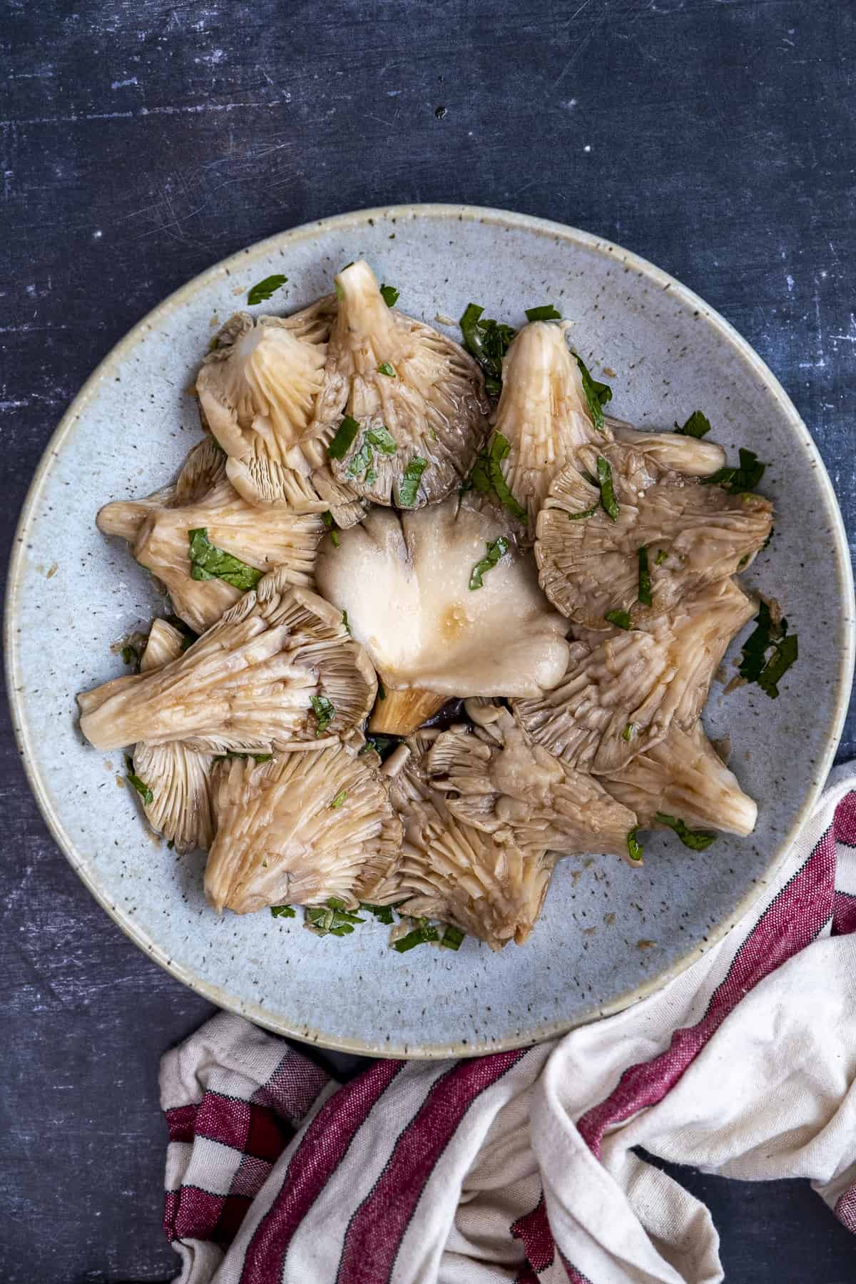 Oyster mushrooms in the marinade sauce in a blueish bowl.