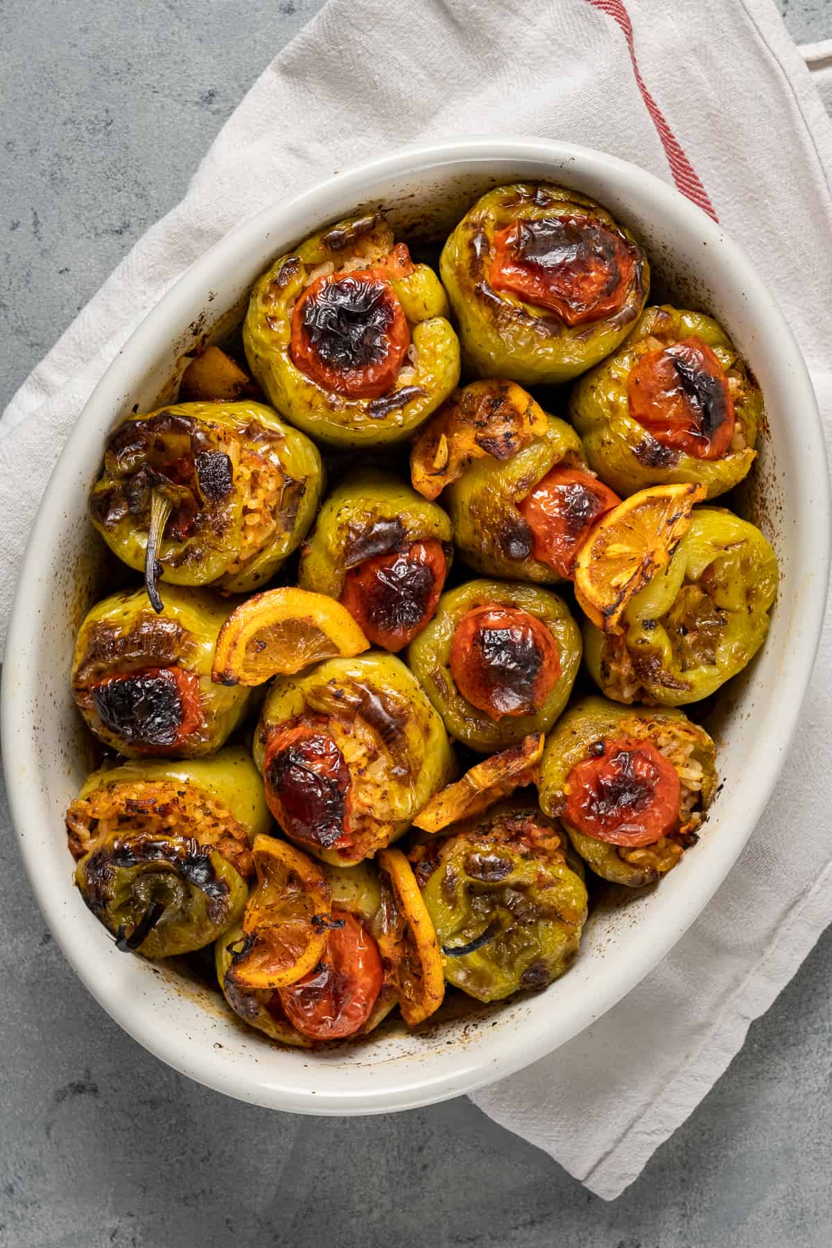 Baked rice stuffed green peppers in a white oval baking pan.