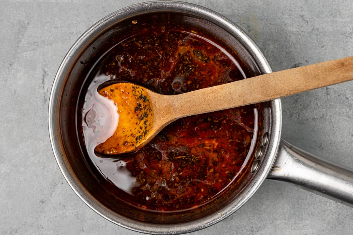 Tomato paste sauce in a sauce pan and a wooden spoon in it.